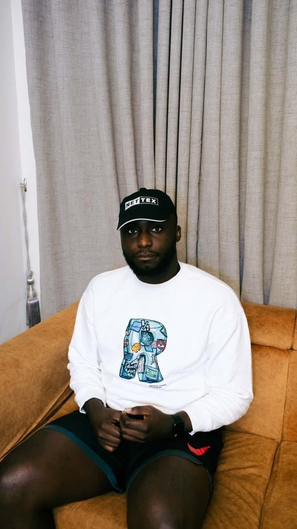 Woriidem seated on an amber sofa in a white sweatshirt